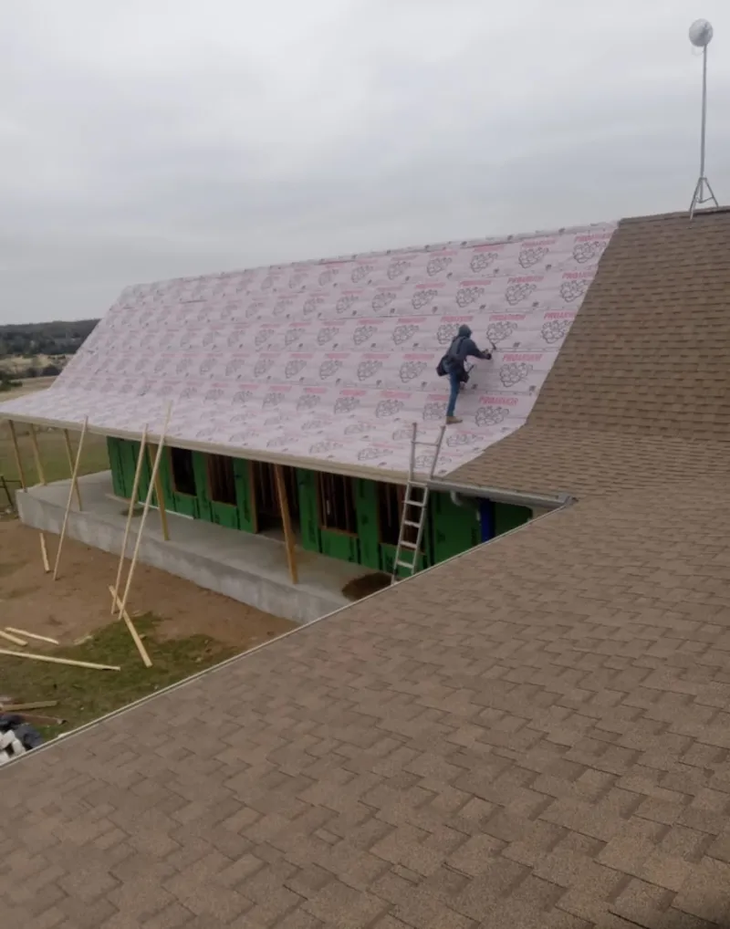 Worker preparing underlayment for a metal roof installation in French Valley